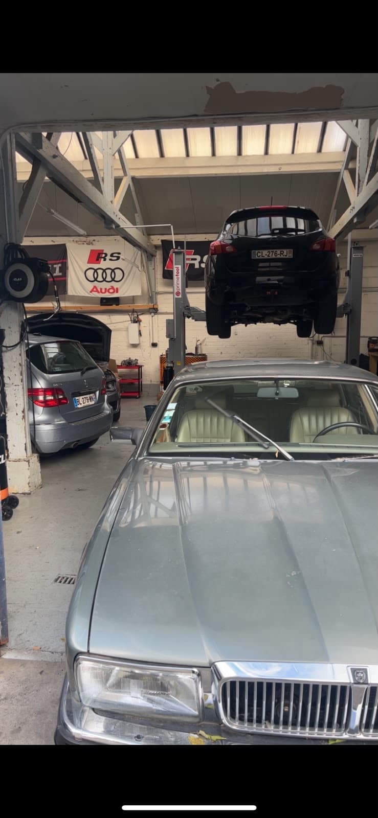 Voiture sur pont élévateur et berline dans l'atelier