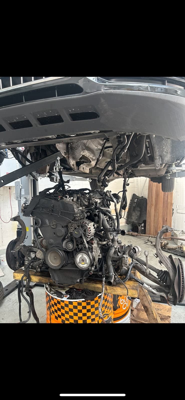 Moteur Audi déposé sous un véhicule sur pont